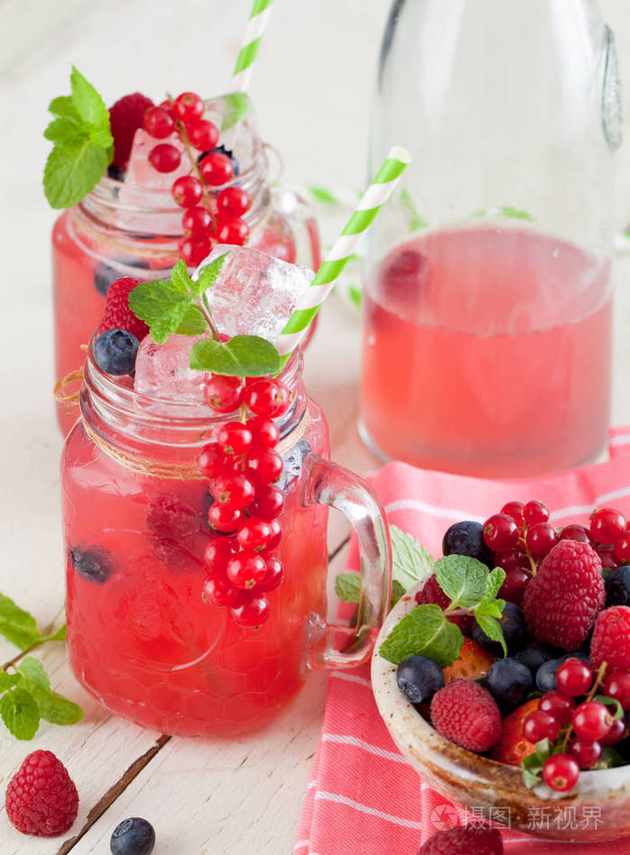 夏日浆果饮料。 柠檬水与覆盆子和黑莓与柠檬薄荷在梅森罐子在白色桌子上。