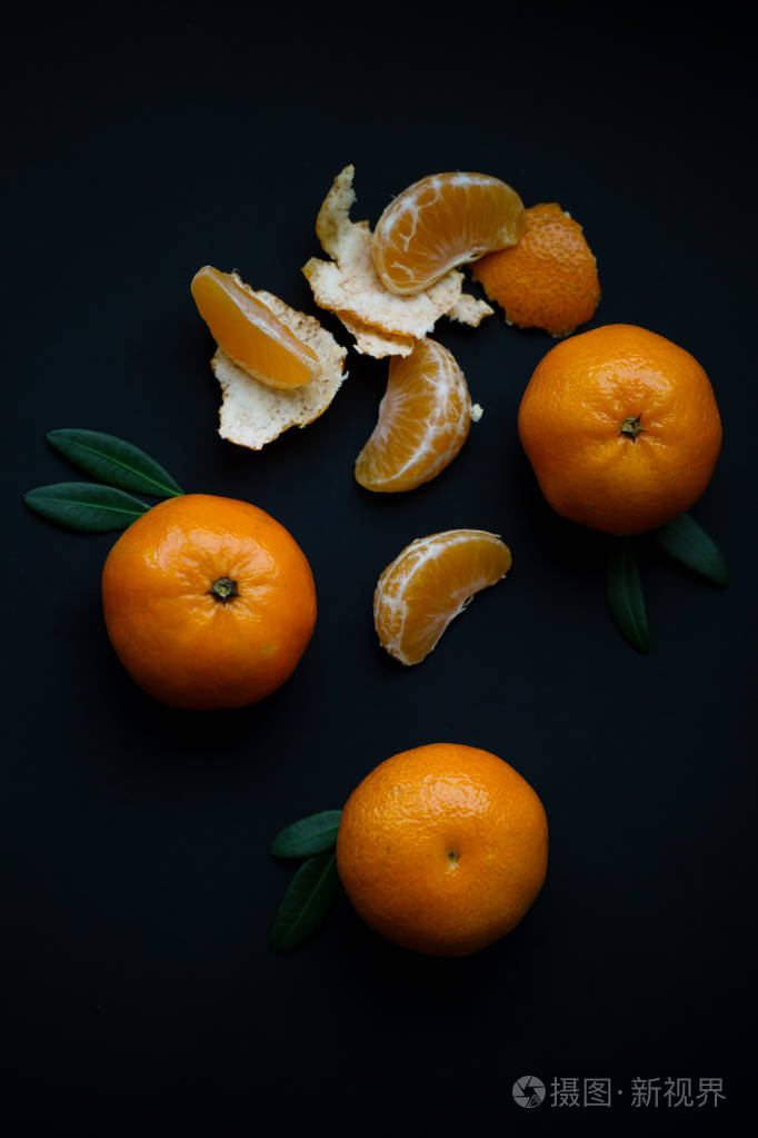 黑色背景下的切片和整个橘子