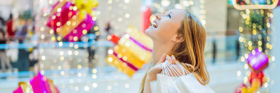 圣诞商场里的年轻女子带着圣诞购物。美女购买圣诞夜购物折扣横幅, 长格式