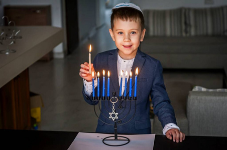 犹太蜡烛图标可爱的白种人犹太男孩点燃蜡烛在传统的光明节男子或烛光