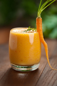 玻璃中的胡萝卜汁和新鲜胡萝卜健康食品，灰色石头背景
