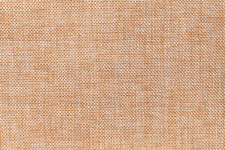 浅橙色和白色背景的密集编织套袋织物特写。 棕色布的结构具有天然的纹理。 布的背景。