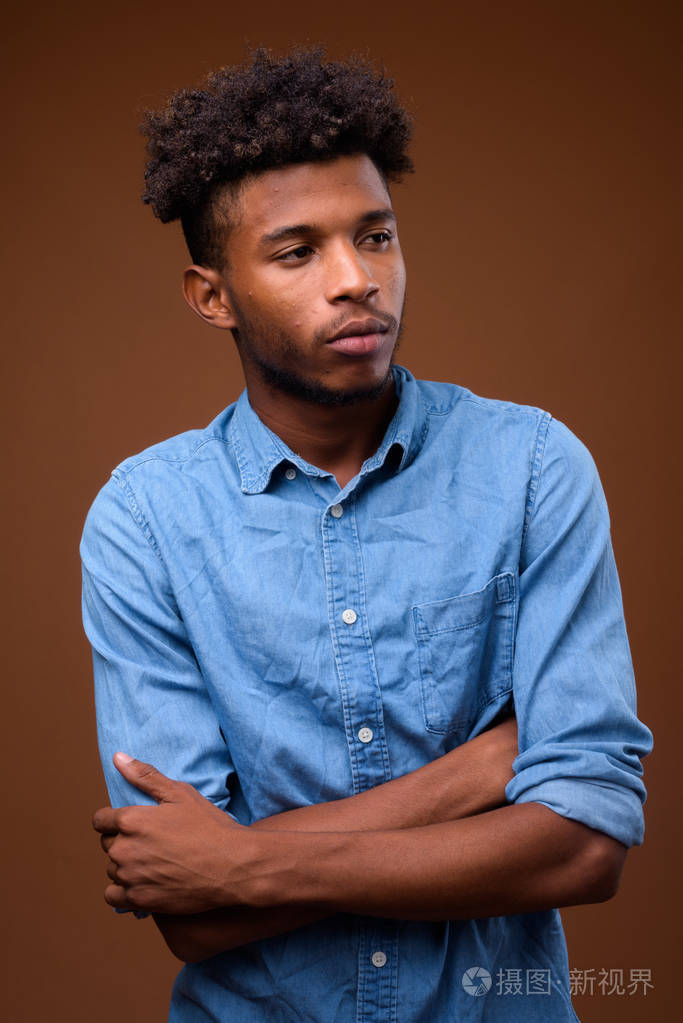 年轻英俊的非洲人认为与棕色背景