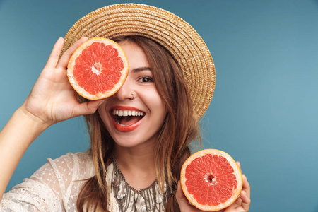 一个快乐的漂亮女人的形象，在蓝色的墙壁背景上与橙色的柑橘隔离。