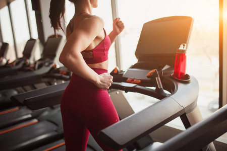 匿名女性在运动服装上跑步的现代跑步机，同时在健身房锻炼