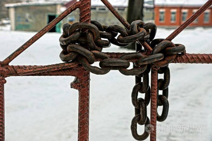 旧的生锈的铁链缠绕在篱笆上