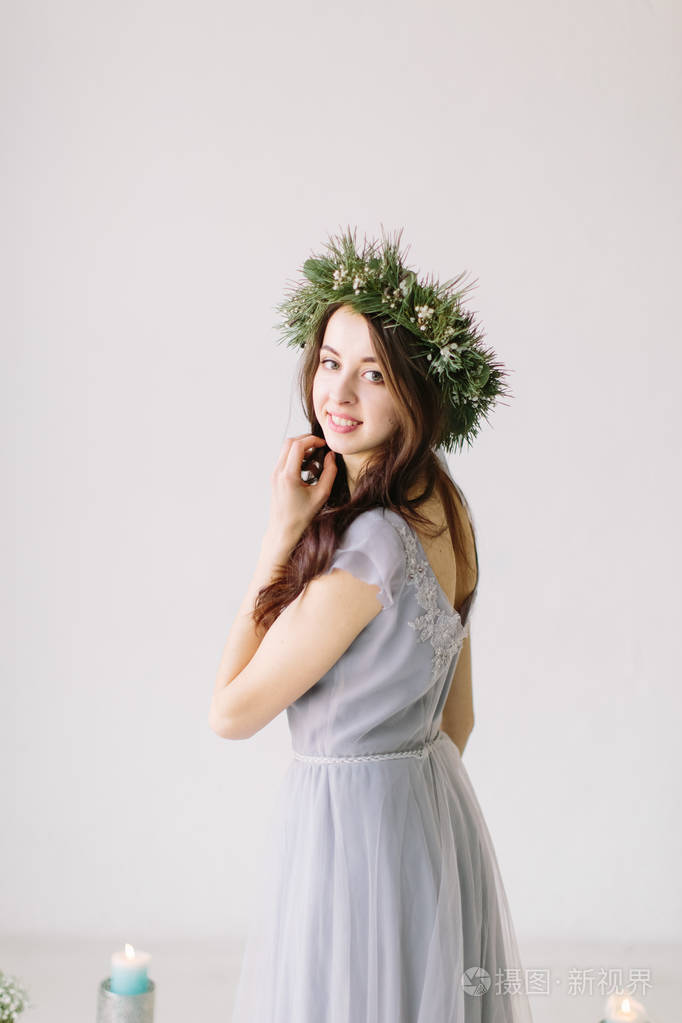 美丽的年轻女孩穿着灰色晚礼服,头上戴着一个松树和桉树花环,在婚礼