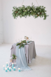 在工作室的桌子上摆着漂亮的装饰着蓝色蜡烛松树鲜花和婚礼蛋糕的桌子