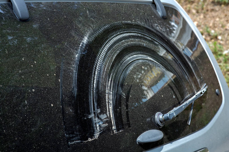 肮脏的汽车视图后玻璃的视图旧损坏的挡风玻璃。