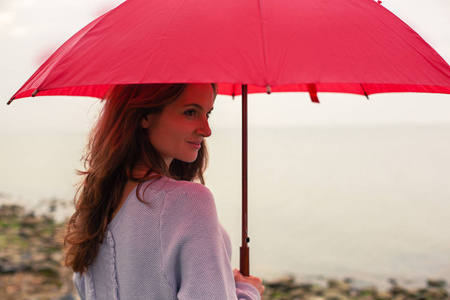 荒滩上带着红伞的年轻女子的肖像。