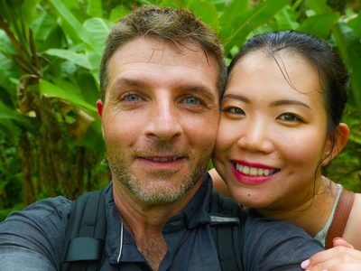年轻美丽快乐的混血儿夫妇美丽的亚裔中国女人和白人男人相爱，在户外自拍，享受浪漫的假期，热带蜜月旅行
