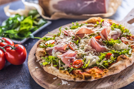 意大利比萨饼与意大利布托，阿鲁古拉西红柿和帕梅桑在木制圆板。