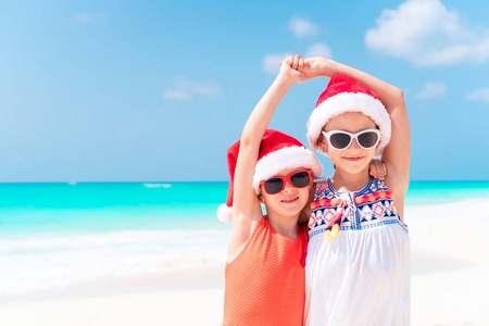 小可爱女孩在圣诞老人的帽子在海滩度假期间就一起玩游戏