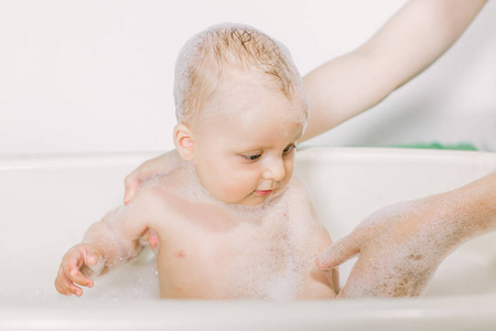 浴缸里的小孩. 婴儿洗涤和洗澡. 卫生和照顾幼儿.照片