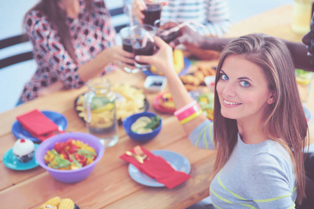 顶视图的一群人在一起时坐在木桌吃饭。在桌子上的食物。人们吃快餐。一个女孩的肖像