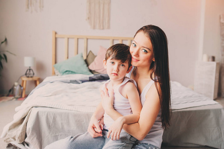 年轻快乐的母亲在卧室安慰孩子. 家庭关系和父母观念休闲生活方式.