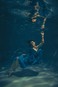 一个穿着蓝色晚礼服的自由潜水员独自在水下游泳