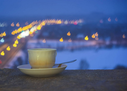 杯子和碟子有模糊的彩色背景。杯子站在一个碟子上，有一个五颜六色的波克。