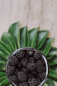 绿色背景上白色杯子里多汁的新鲜黑莓。 有机健康浆果。