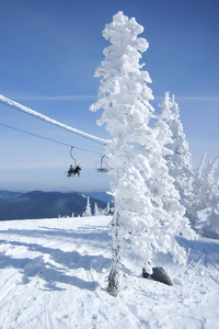  two skiers on chairlift above the mountain slope