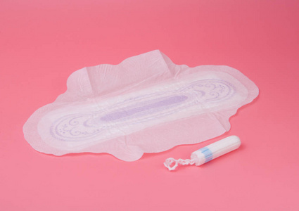 棉质医用毛巾或垫，用于粉红背景下的女性关键日子。 关心和保护。