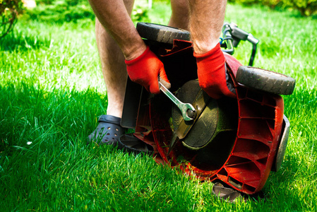 s knife with a new one. Mowing the grass. Gardener mows the gras