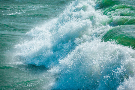 蓝绿色海水表面有波浪喷雾和白色泡沫