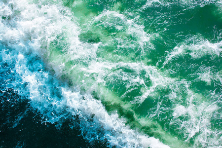 蓝绿色海水表面有波浪喷雾和白色泡沫