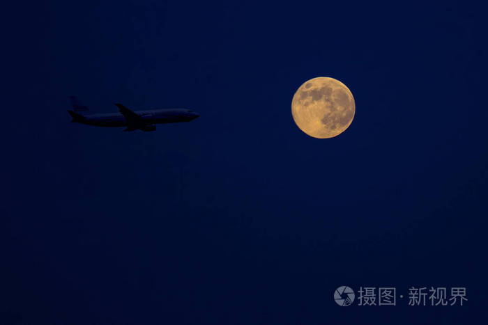 满月背景下夜空中的大型客机