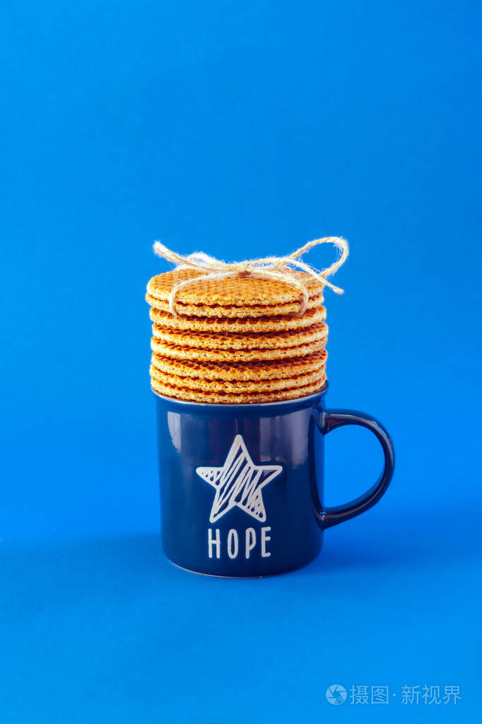 荷兰华夫饼称为蓝色背景上的斯特罗帕菲尔配有蓝色的茶或咖啡