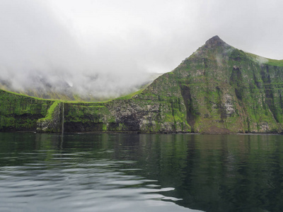 陡峭的绿色霍恩比格列格悬崖和瀑布, 欧洲最大的鸟崖, 西峡湾, 冰岛偏远的自然保护区霍恩斯特兰迪尔, 雾蒙蒙的雾海和喜怒无常的天