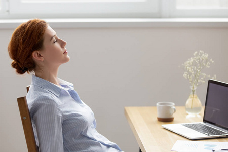 侧视图女性休息与闭着眼睛在工作照片