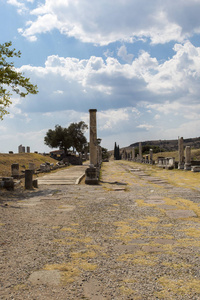 古罗马道路的全景垂直景观，道路两旁有柱子，映衬着古城阿克里皮翁的蓝天