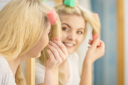 金发女人用卷发器在她的发型上创造美丽的发型。