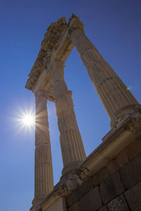 在明亮的太阳背景下，关闭希腊罗马风格的高大古柱。
