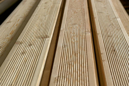 露台板落叶松与带材建材在仓库。 未油漆的槽木露台木板堆叠。