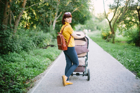 有婴儿车的母亲的完整肖像。年轻妈妈