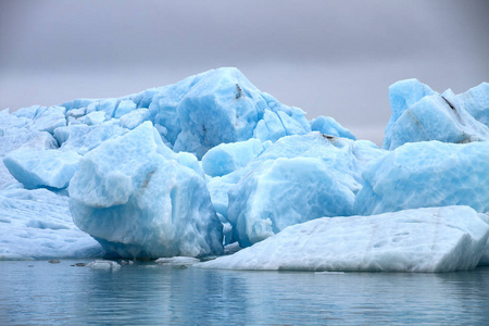 一大块蓝色的冰川，漂浮在灰色天空的水面上
