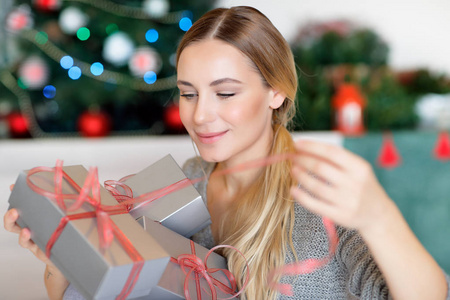 喜欢圣诞礼物的好女人，期待着打开所有的礼盒，带着装饰精美的圣诞树在家度过寒假