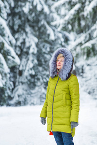 一个年轻的女人正在白雪覆盖的树木之间穿过冬林