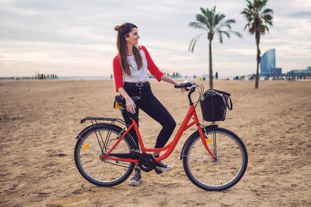 妇女骑自行车沿海滩沙子在夏天时间