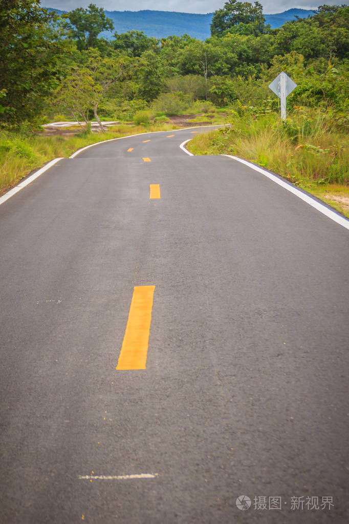 新蜿蜒的沥青道路在农村地区弯曲黄线在两条车道的中间分割