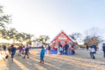 摘要模糊的弹跳屋和排队排队排队的父母和孩子在姜饼禧年在住宅区附近的公共公园，达拉斯，德克萨斯州，美国