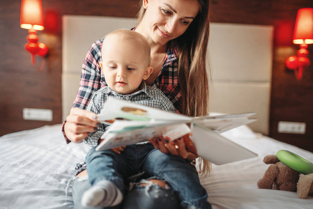 年轻的母亲和小男孩读一本书，孩子教育。 妈妈和儿子在一起快乐