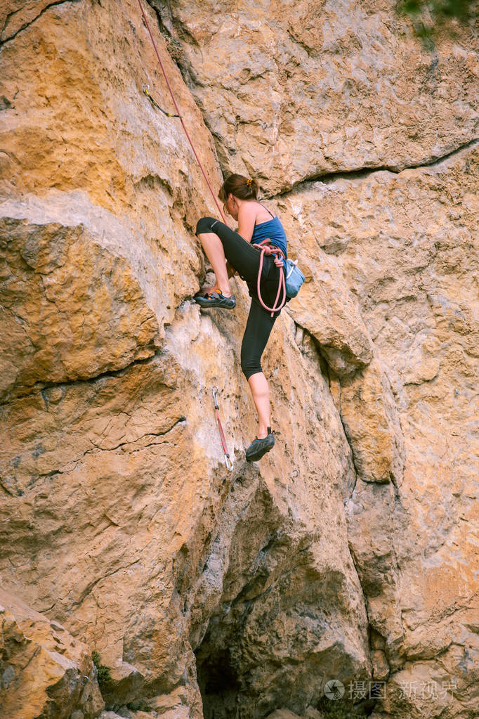 女孩爬上岩石。登山者正在训练攀岩.强壮的运动员克服了艰难的攀登路线。极端的爱好。一个女人在大自然中参加运动。天然岩石地形。