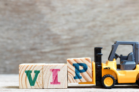 玩具叉车持有字母块p完成单词vip非常重要的人的缩写在木材背景上