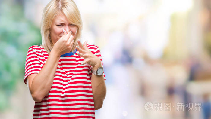 年轻漂亮的金发女人在孤立的背景上闻到一些臭味和令人恶心的难以忍受