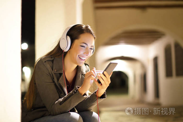 幸福的女人在夜里坐在街上听音乐