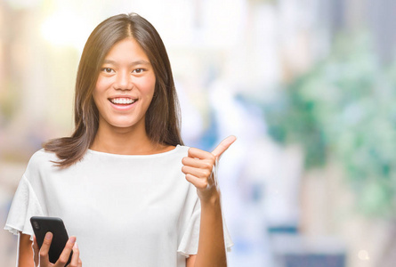 年轻的亚洲女人用智能手机在孤立的背景上发短信,开心地大笑着做,好的