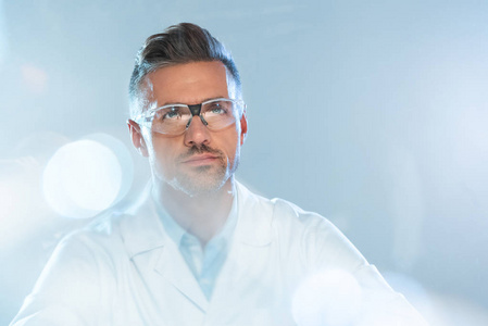 戴防护眼镜的英俊科学家的肖像，孤立地仰望白色人工智能概念